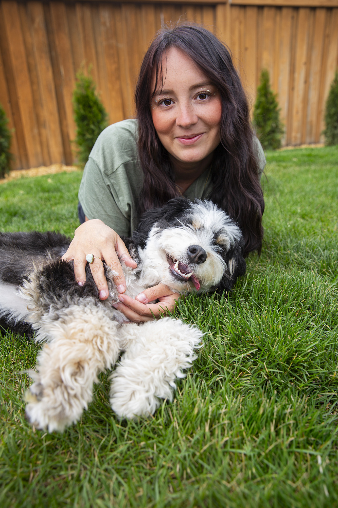 Elaine laying in grass with green shirt with her dog.