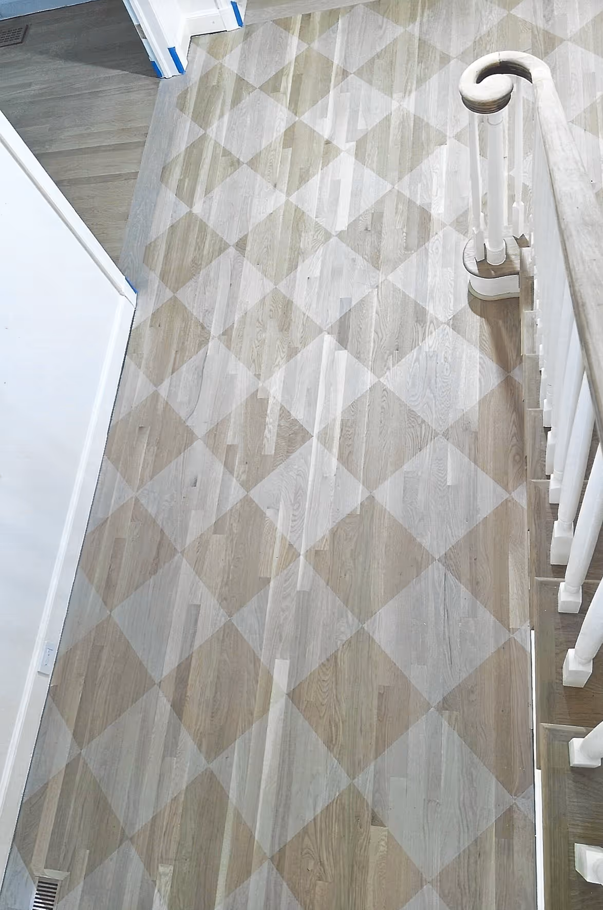 Wooden staircase with white handrails and a geometric patterned floor covering.