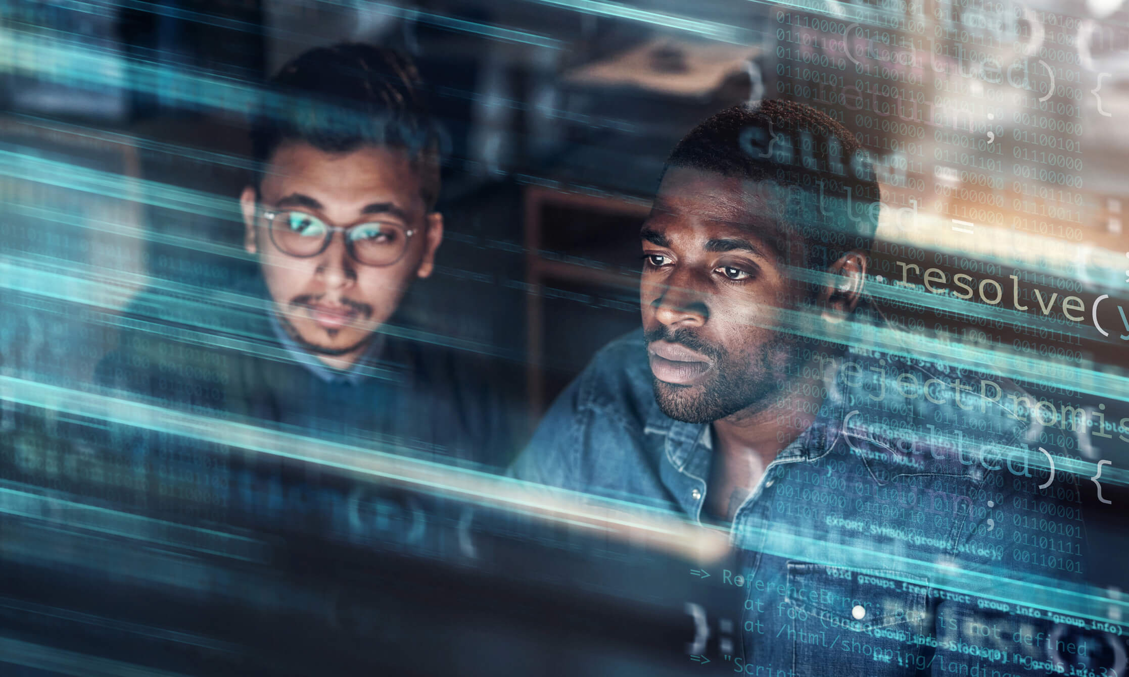 Two focused men working together in a dimly lit room, viewed through a transparent screen displaying lines of computer code and binary numbers.