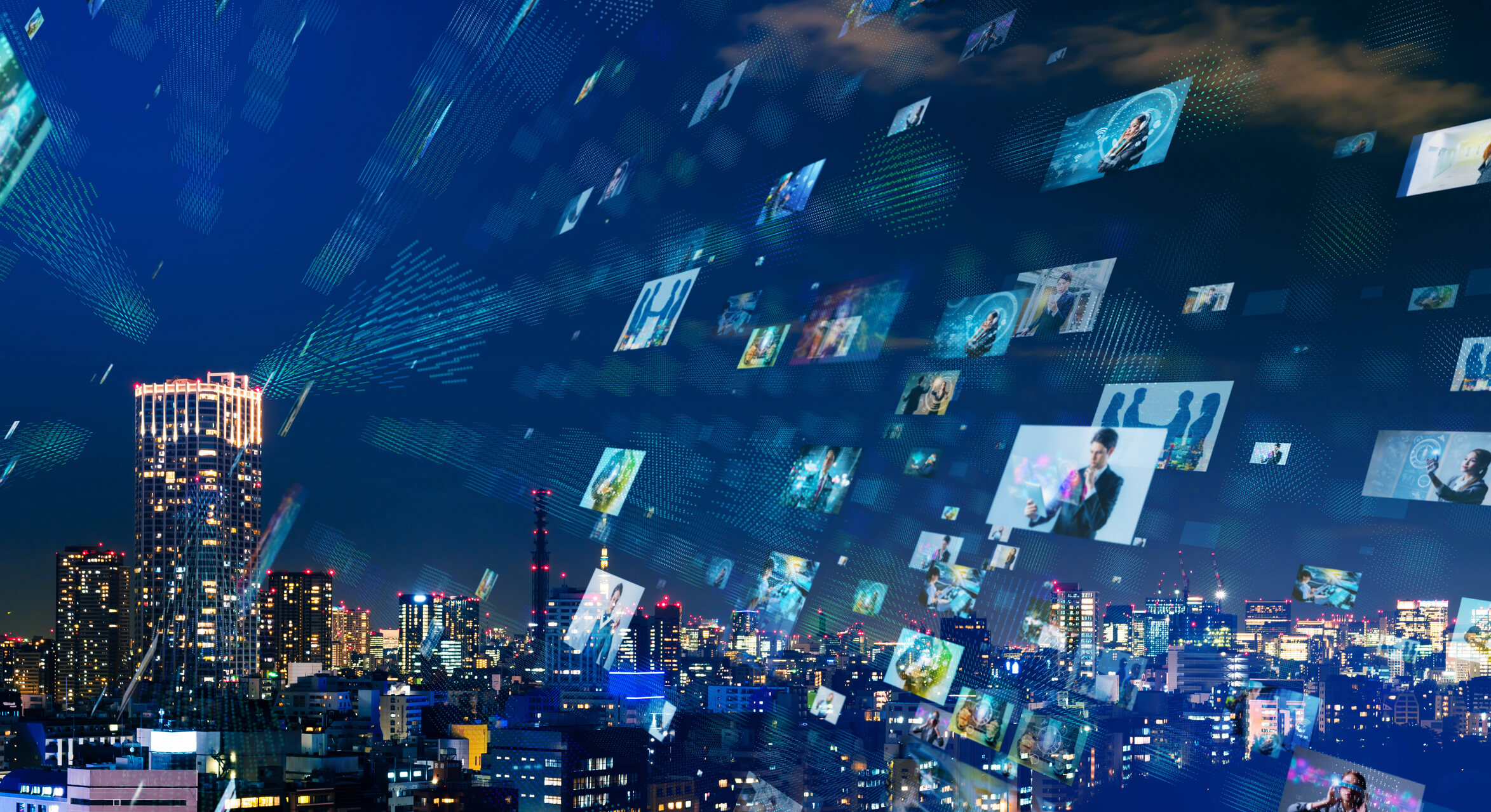 Cityscape at night with illuminated skyscrapers beneath a sky filled with floating digital images of people and technology, representing virtual communication and data exchange.