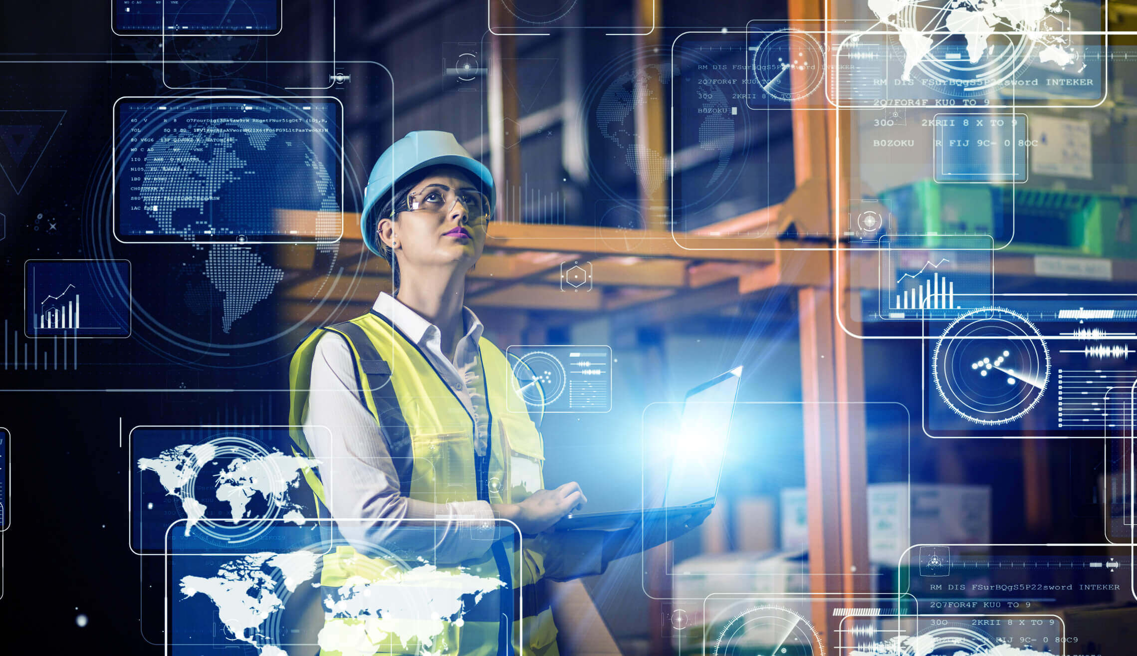 A woman wearing a safety helmet, glasses, and a yellow safety vest holds a laptop in a warehouse with shelves and boxes, surrounded by transparent digital world maps and data graphics overlays.