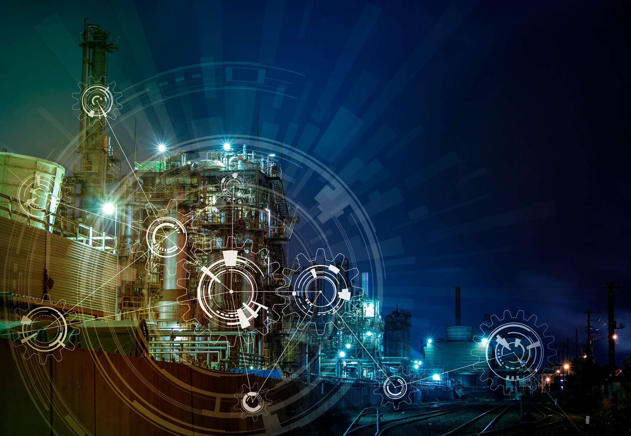 Night view of an industrial plant with illuminated structures and pipes overlaid with digital gear and technology interface graphics, symbolizing industrial automation and smart manufacturing.