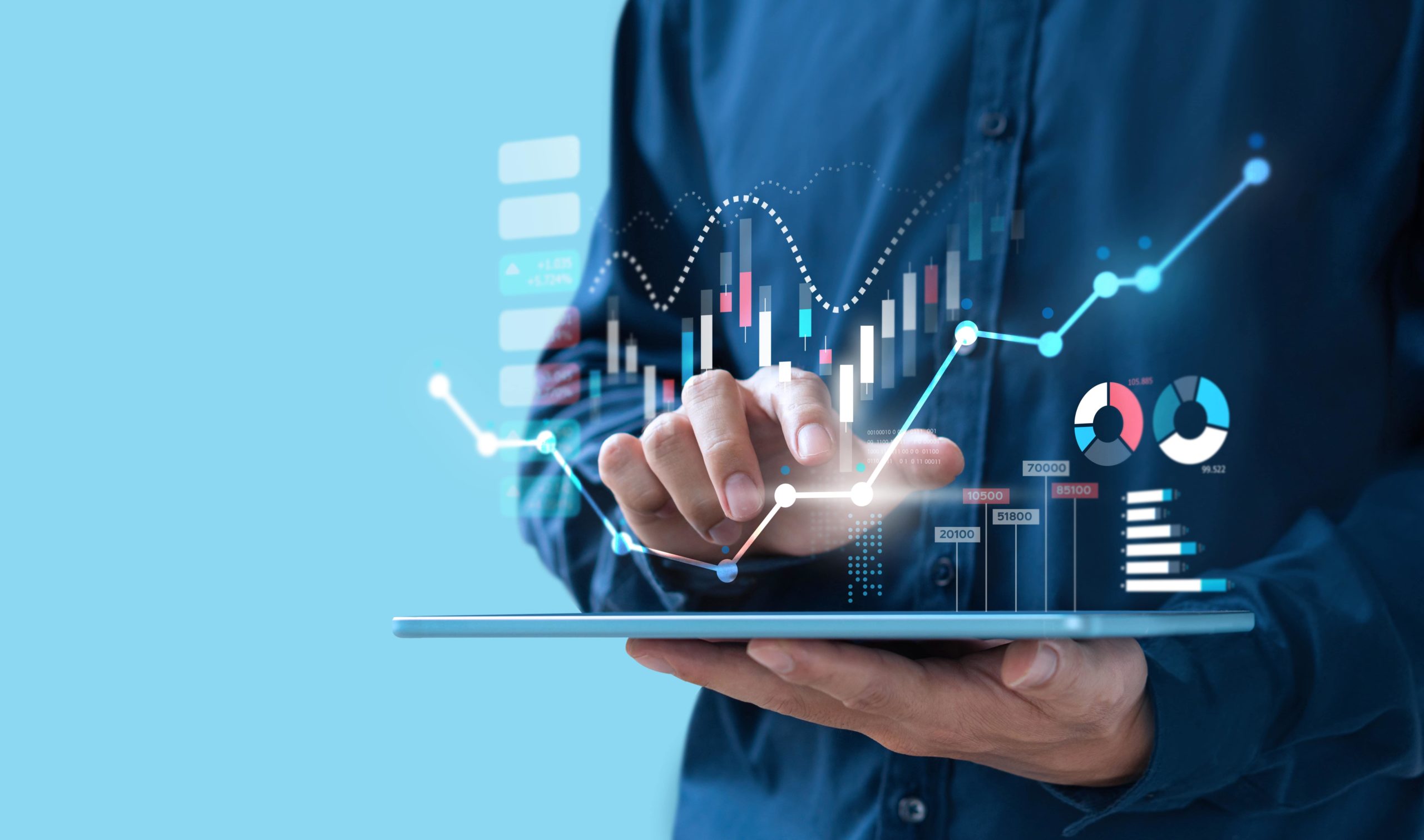 Person in dark blue shirt holding a tablet with virtual financial charts, graphs, and data visualizations appearing above the device.