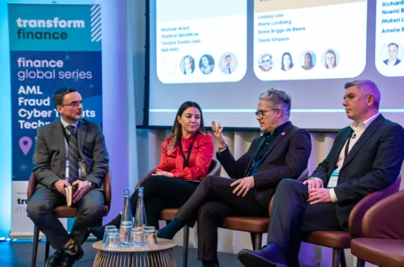 Four panelists seated on stage during a transform finance event, with a banner about finance global series featuring AML, fraud, and cybersecurity topics visible in the background, and a projected slide showing participant names and photos.