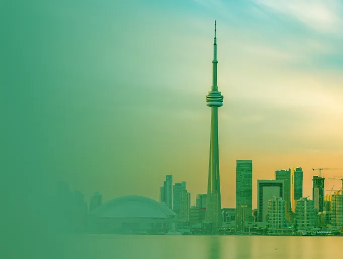City skyline at sunset featuring the CN Tower and nearby modern buildings reflected on the calm water.
