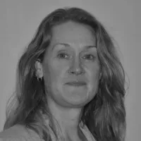 Black and white portrait of a woman with wavy hair, looking at the camera with a slight smile, wearing earrings and a jacket.