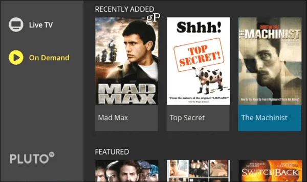 Screenshot of Pluto TV interface showing Live TV and On Demand options with On Demand selected; recently added movies displayed include Mad Max, Top Secret, and The Machinist, with a featured section partially visible below.