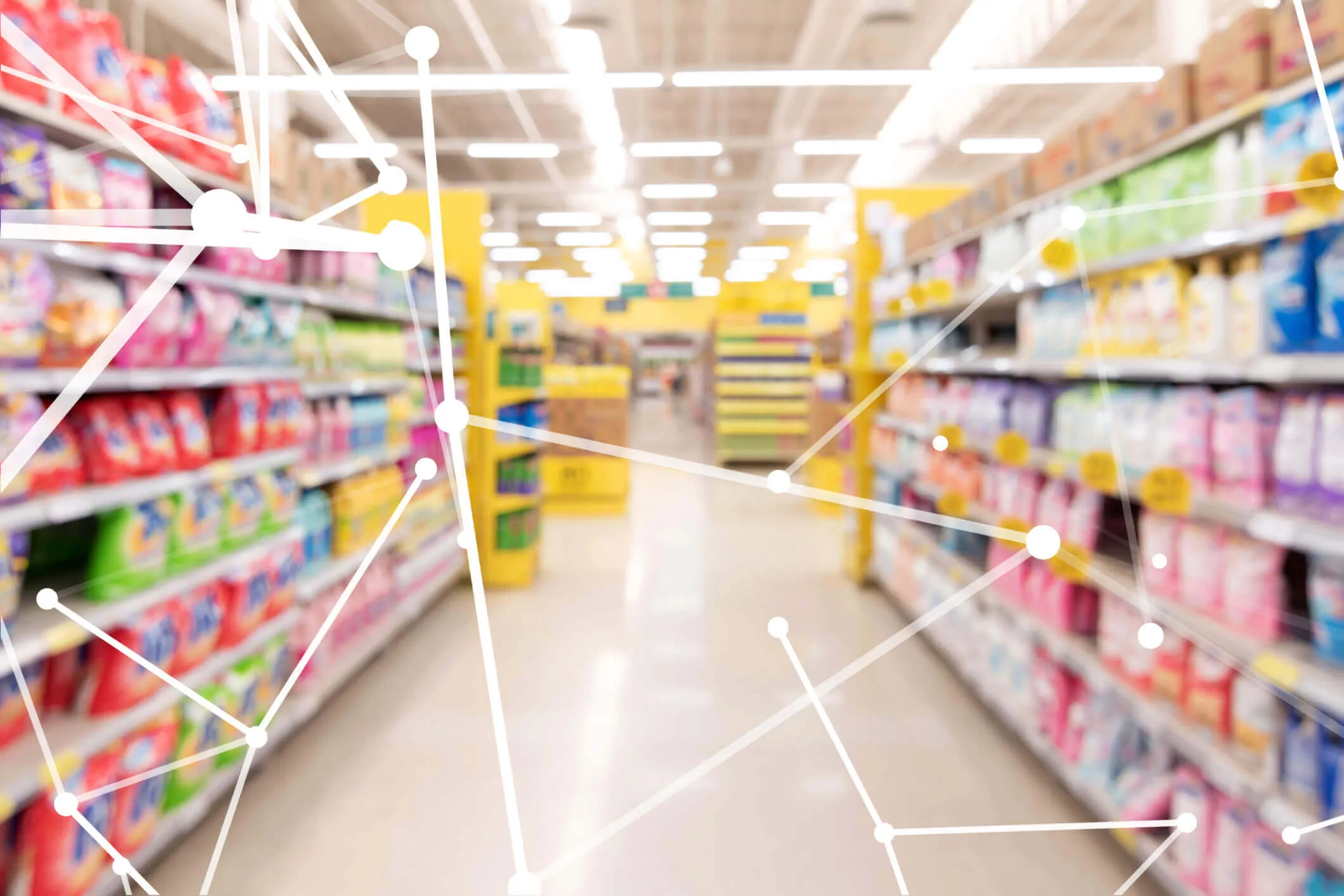 Blurred view of supermarket aisles stocked with colorful products on both sides, overlaid with white network lines and dots representing digital connectivity or AI technology.