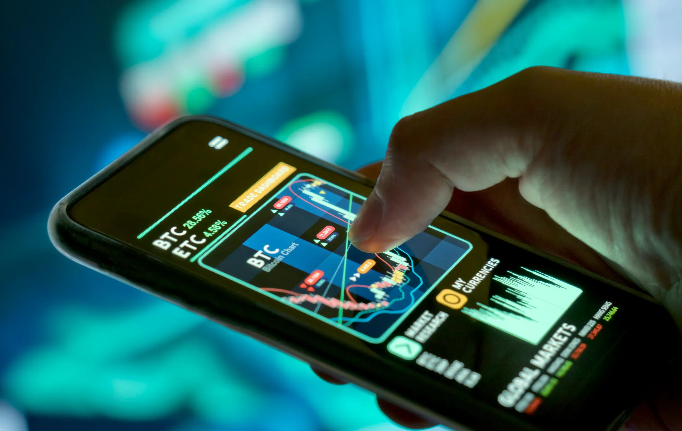 Hand holding smartphone displaying a cryptocurrency trading app with BTC and ETC prices, a candlestick chart, and market statistics on screen.