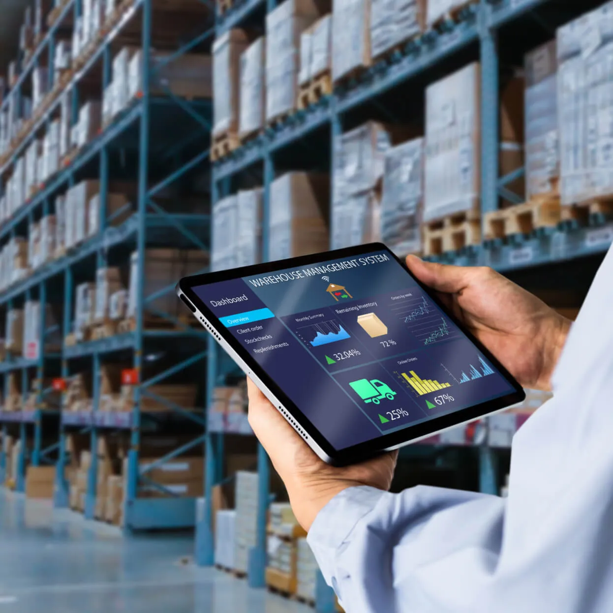 Person holding a tablet displaying a warehouse management system dashboard with charts and metrics, standing in a warehouse with shelves stacked with boxes and pallets.