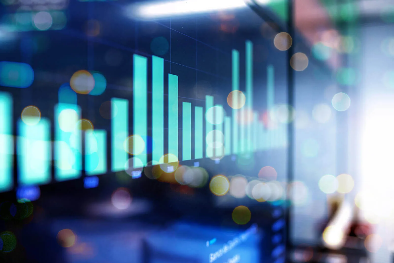 Blurred digital bar chart with glowing blue and turquoise bars representing data, set against a dark background with bokeh light effects.