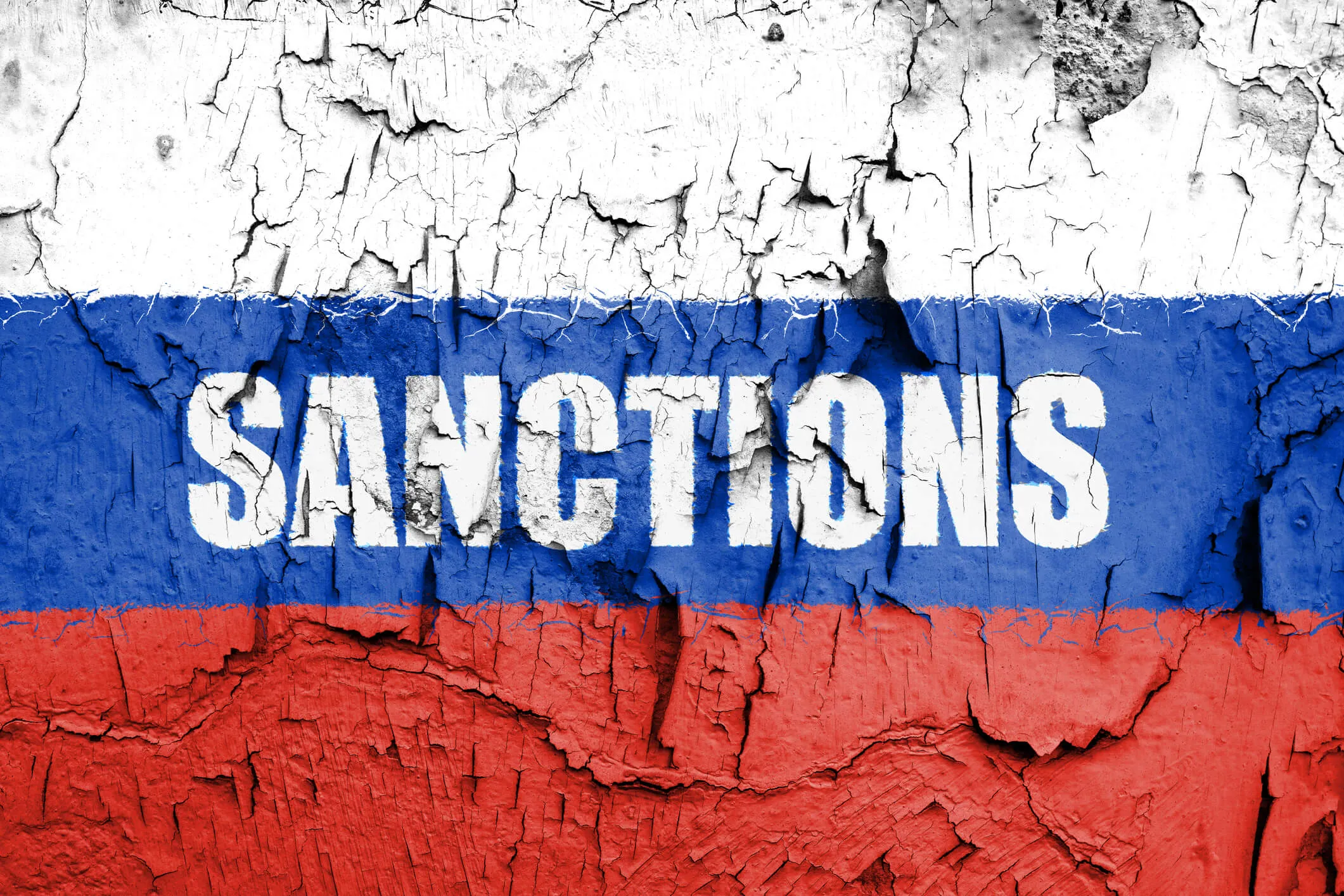 Cracked, peeling paint in white, blue, and red stripes resembling the Russian flag, with the word SANCTIONS stenciled in white across the blue stripe.