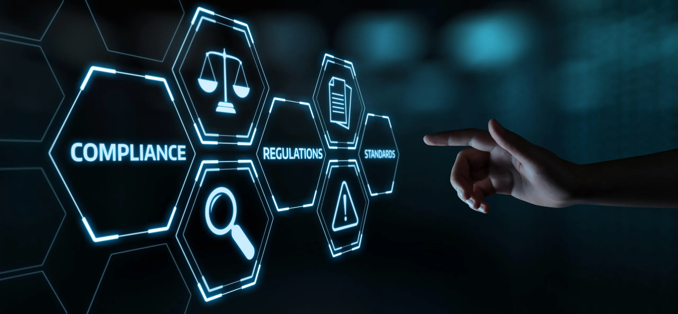 A hand pointing towards glowing blue hexagonal icons displaying compliance-related terms and symbols, including scales of justice, magnifying glass, warning symbol, document, and words compliance, regulations, and standards on a dark background.
