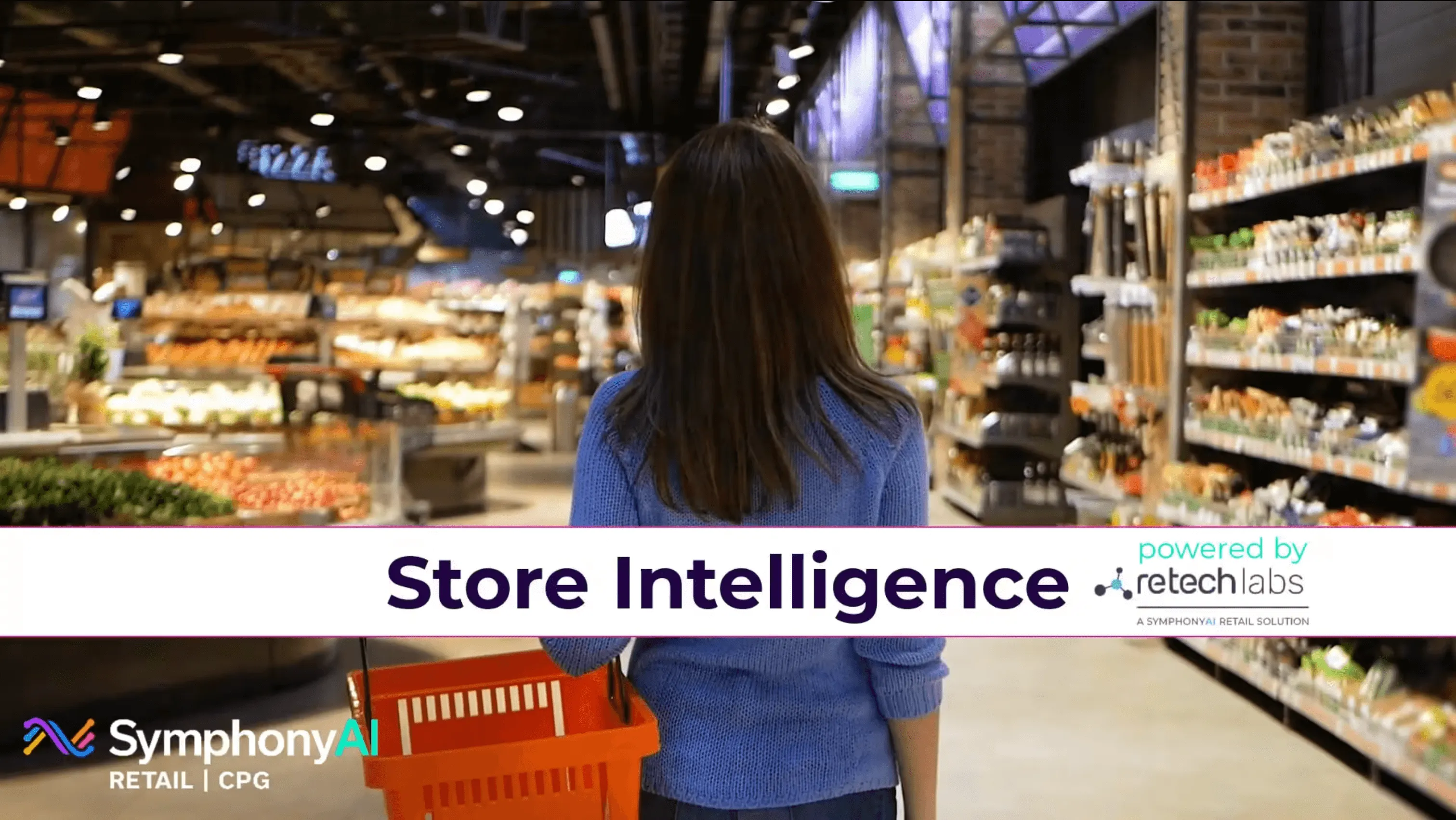 Person with long dark hair wearing a blue sweater holding an orange shopping basket walking through a brightly lit supermarket aisle with stocked shelves on the right and produce displays on the left, overlaid with the text 'Store Intelligence powered by retechlabs' and the SymphonyAI Retail | CPG logo.