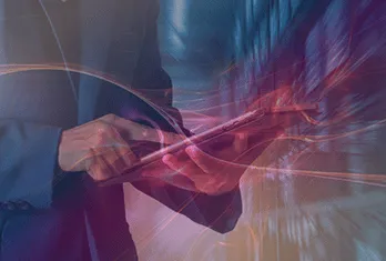 Person in a suit holding and using a tablet device with dynamic light trails and reflections around, suggesting technology and connectivity.