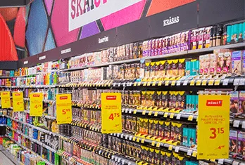 Supermarket aisle shelves stocked with various packaged snacks and food items, with several yellow price labels showing discounts in red text.