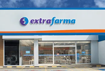 Exterior of an Extrafarma pharmacy with glass doors and shelves visible inside under a cloudy sky.