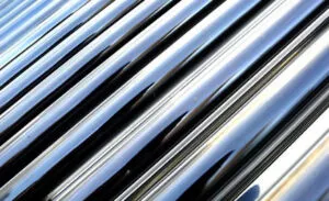 Close-up of several parallel, shiny metallic pipes reflecting light.