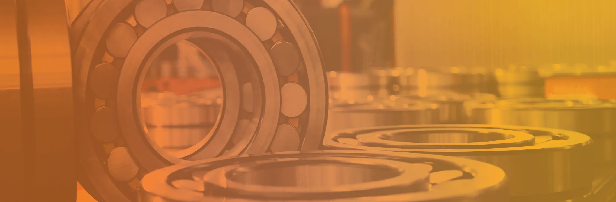 Close-up view of several metal ball bearings arranged on a flat surface with an orange-yellow gradient overlay.