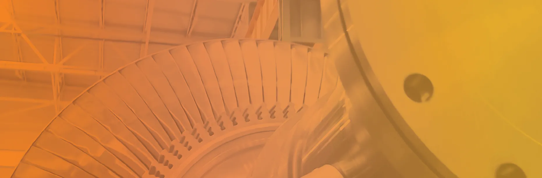 Close-up of a large industrial turbine or fan blade assembly inside a facility with a metal roof structure visible in the background.