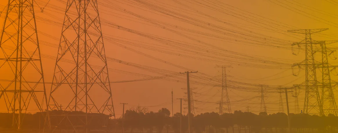 Multiple electricity transmission towers and power lines stretching across a landscape with trees in the background, shown at sunset or sunrise with an orange gradient overlay.