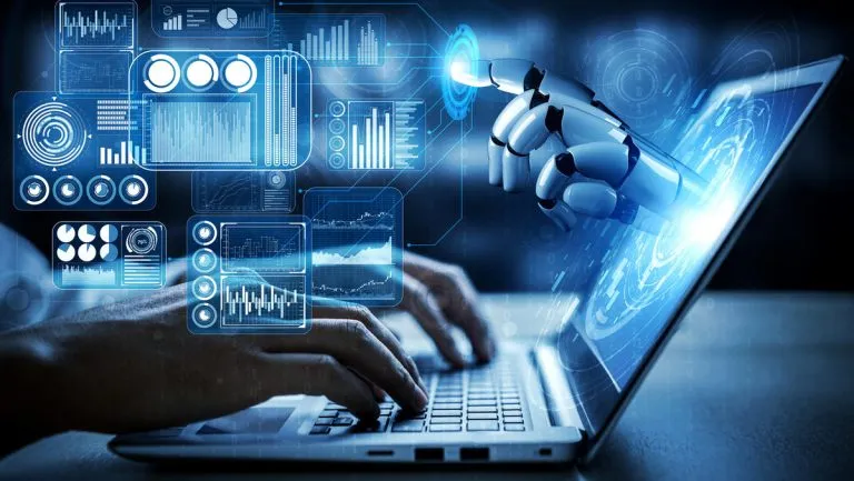 Human hands typing on a laptop keyboard with a robotic hand emerging from the screen, interacting with digital data visualizations and charts floating above the keyboard.