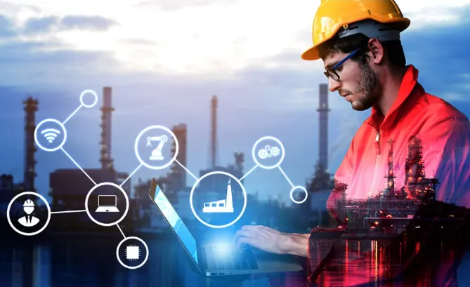 Engineer wearing a yellow hard hat and red jacket working on a laptop with an industrial plant in the background, overlaid with icons representing connectivity, automation, and industrial technology.