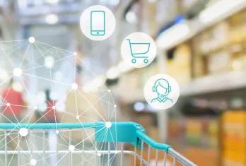 Close-up of a shopping cart handle inside a retail store with blurred shelves in the background and digital icons representing a smartphone, shopping cart, and customer support connected by network lines.
