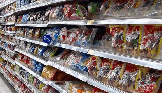 Grocery store shelves filled with various colorful packaged snacks arranged in rows, taken at an angle showing multiple rows and brands.