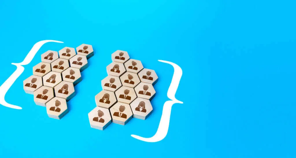 Two groups of wooden hexagonal blocks with icons of people in business attire, each group enclosed by white curly braces on a blue background, symbolizing team division or organizational structure.