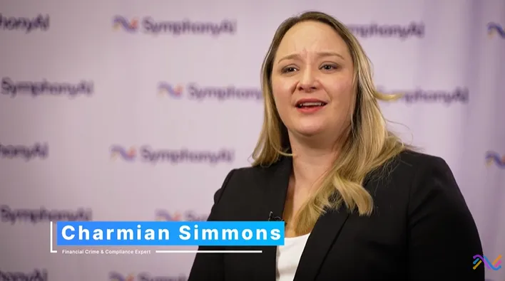 A woman with long blond hair, wearing a black blazer and white top, stands in front of a backdrop with repeated SymphonyAI logos. The lower third text identifies her as Charmian Simmons, Financial Crime & Compliance Expert.