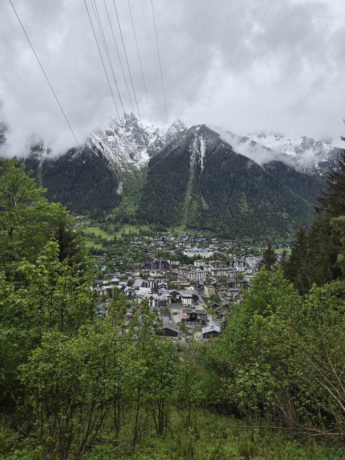 View of Chamonix town nestled in the valley, clouds hanging low over snow-dusted peaks