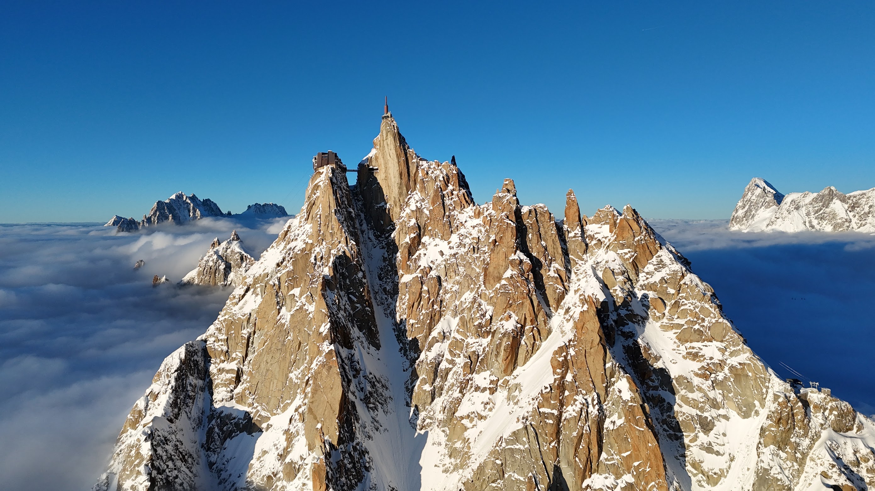 Dramatic sunset view of alpine peaks rising above a sea of clouds filling the Chamonix valley