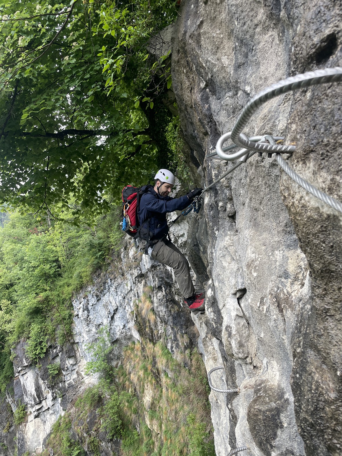Climber moving through the gorge section of the via ferrata on wet iron rungs