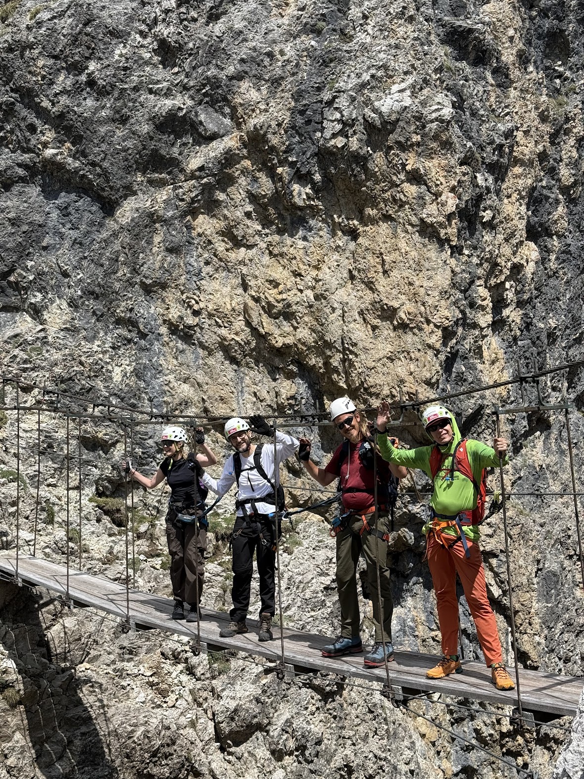 The suspension bridge at the top of Via Ferrata Tridentina, climbers crossing below the rock face