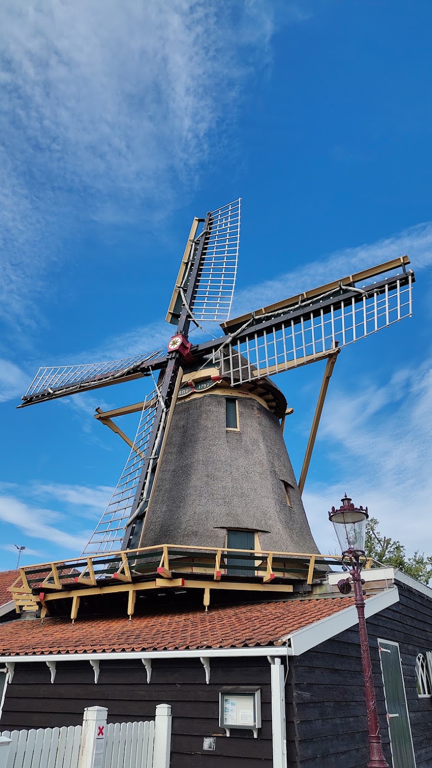 A traditional Dutch windmill with its sails turning against a blue sky