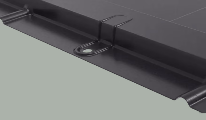 Close-up of a black metal roofing panel with a raised seam and attached clip.