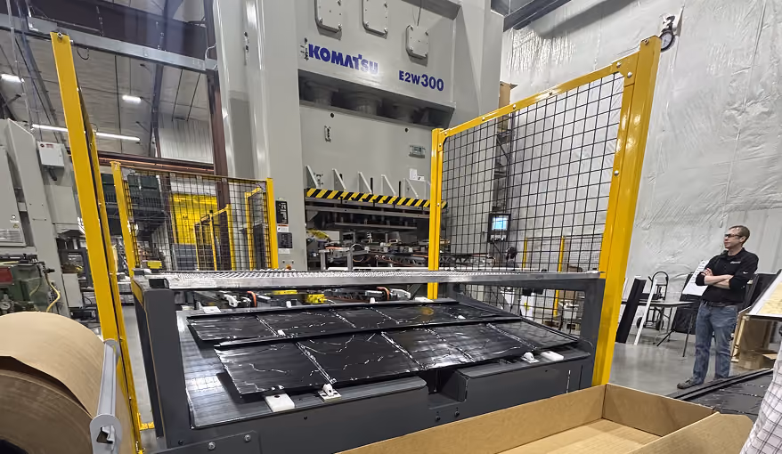 Industrial manufacturing equipment with solar panels on a conveyor belt inside a factory.