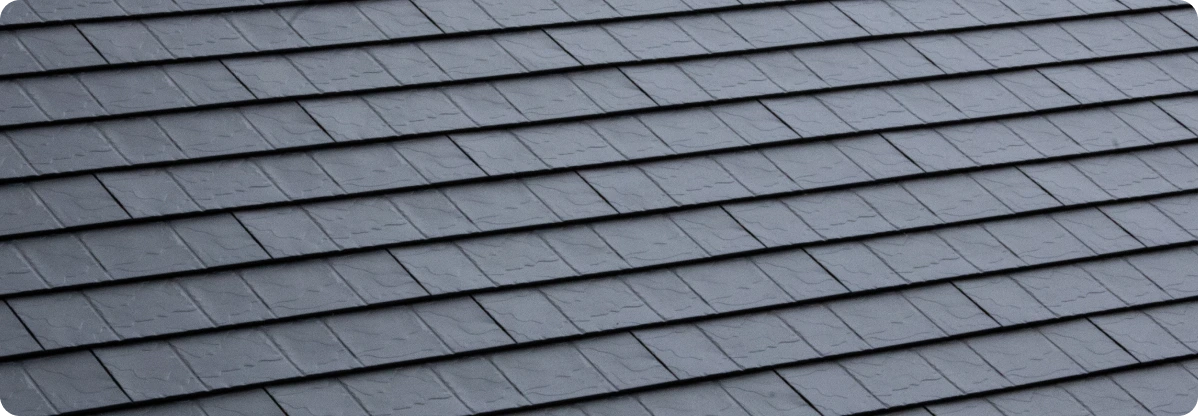 Close-up view of gray, textured roof shingles arranged in overlapping horizontal rows.