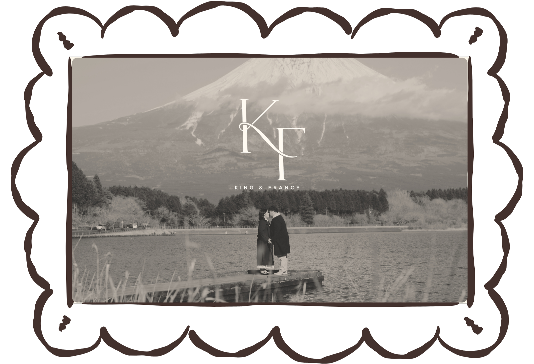 Couple kissing by a lake with trees and mountains framed in an ornate oval frame, King & France text.