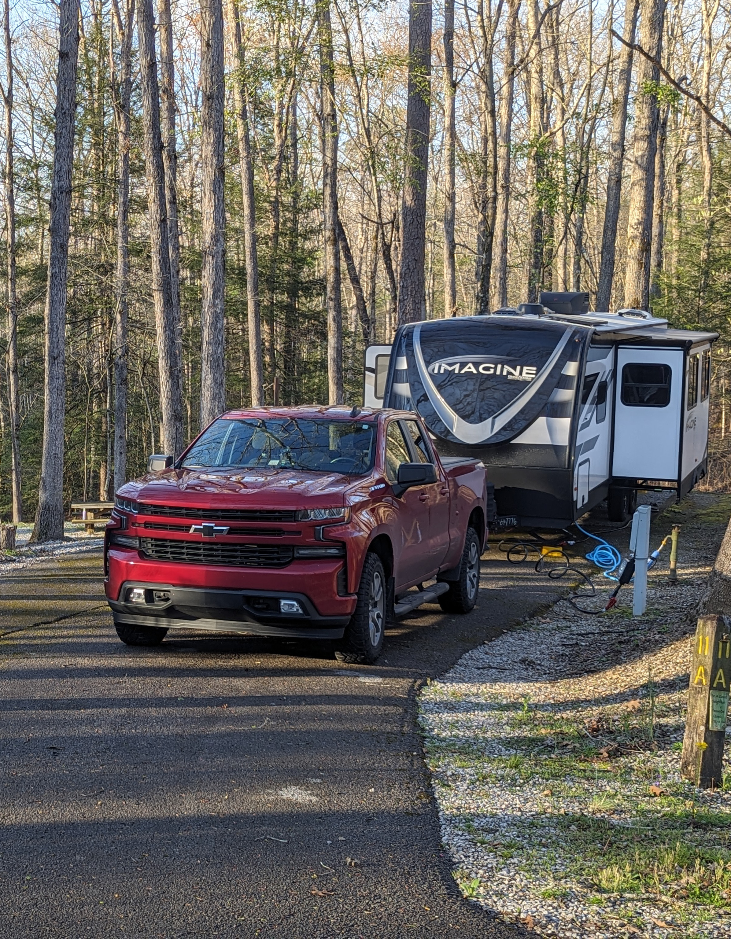 Truck and trailer positioned on it's campground site in the woods.