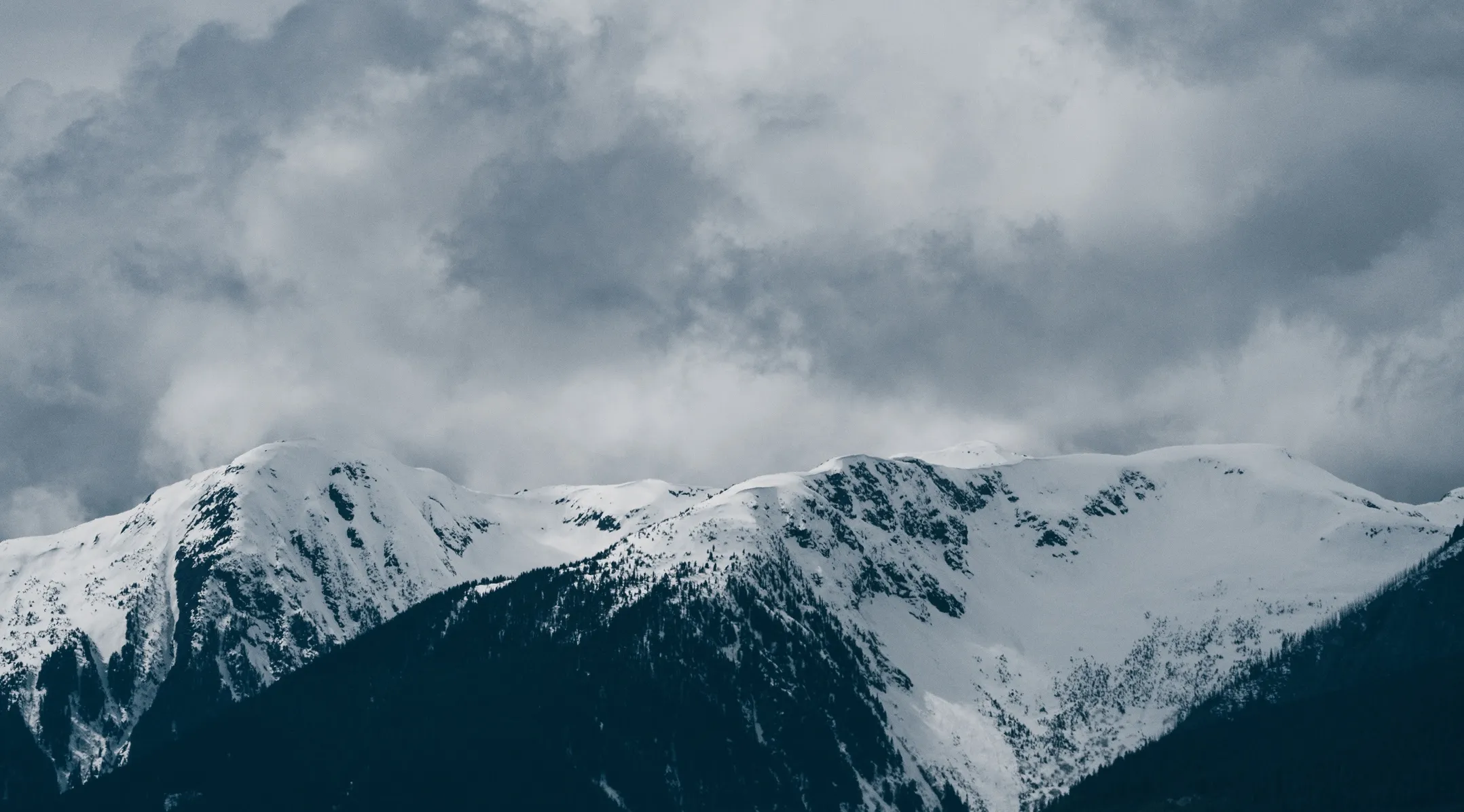 Snow-covered mountain peaks beneath a cloudy sky.