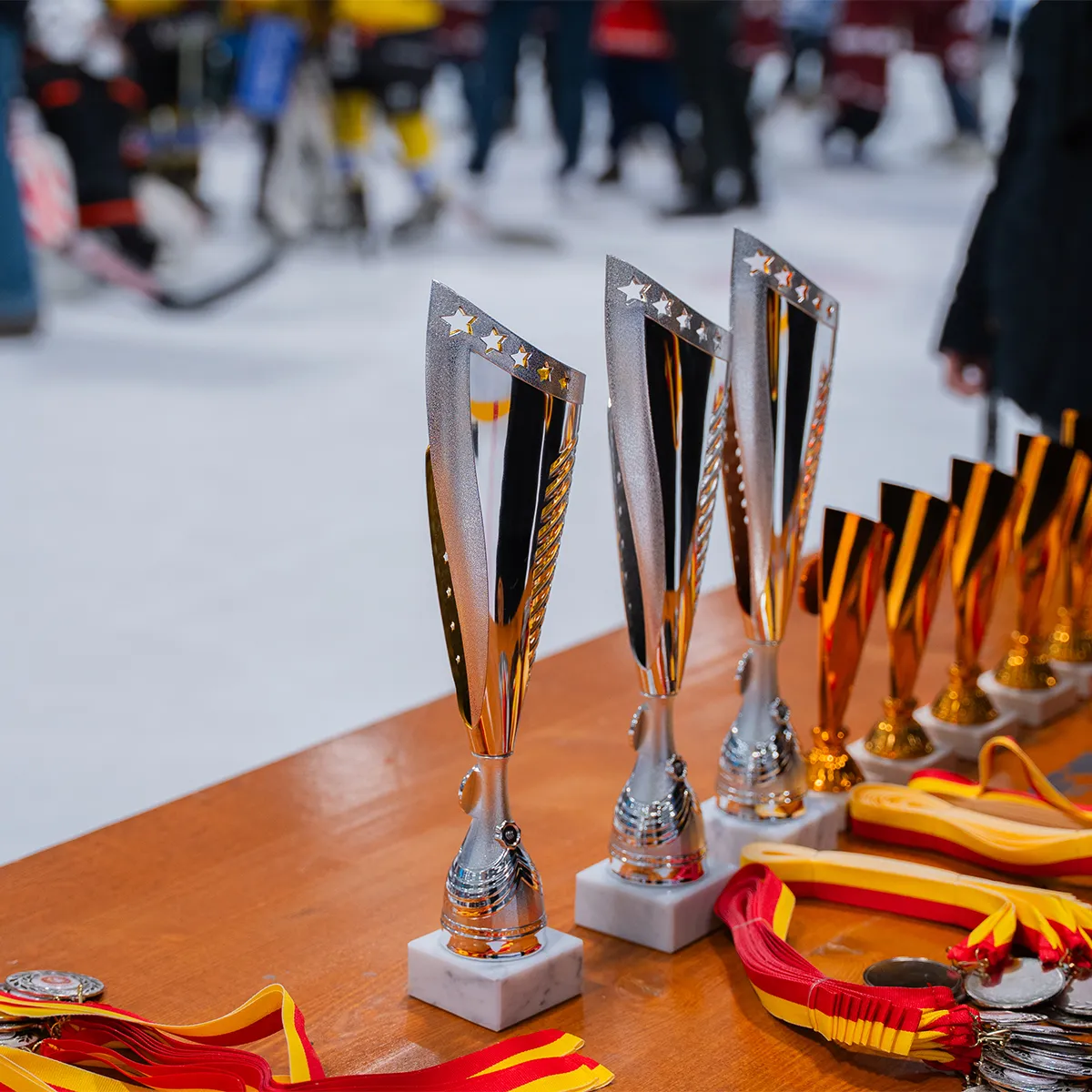 Trois grands trophées argentés avec étoiles sur une table devant plusieurs petits trophées dorés.