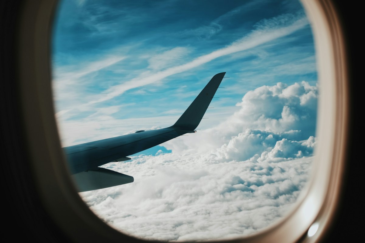 Plane wing seen through a cabin window above the clouds