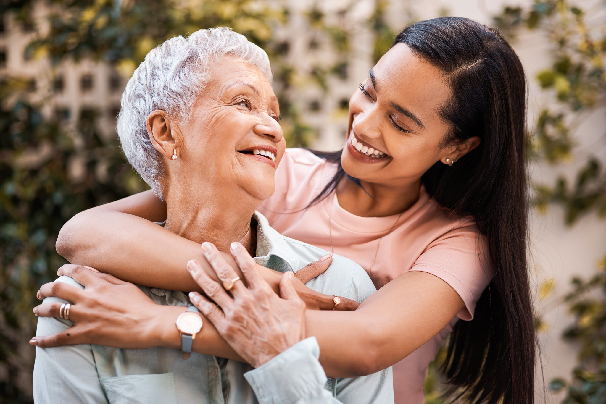 An older woman and a younger woman embracing warmly in a tender intergenerational moment