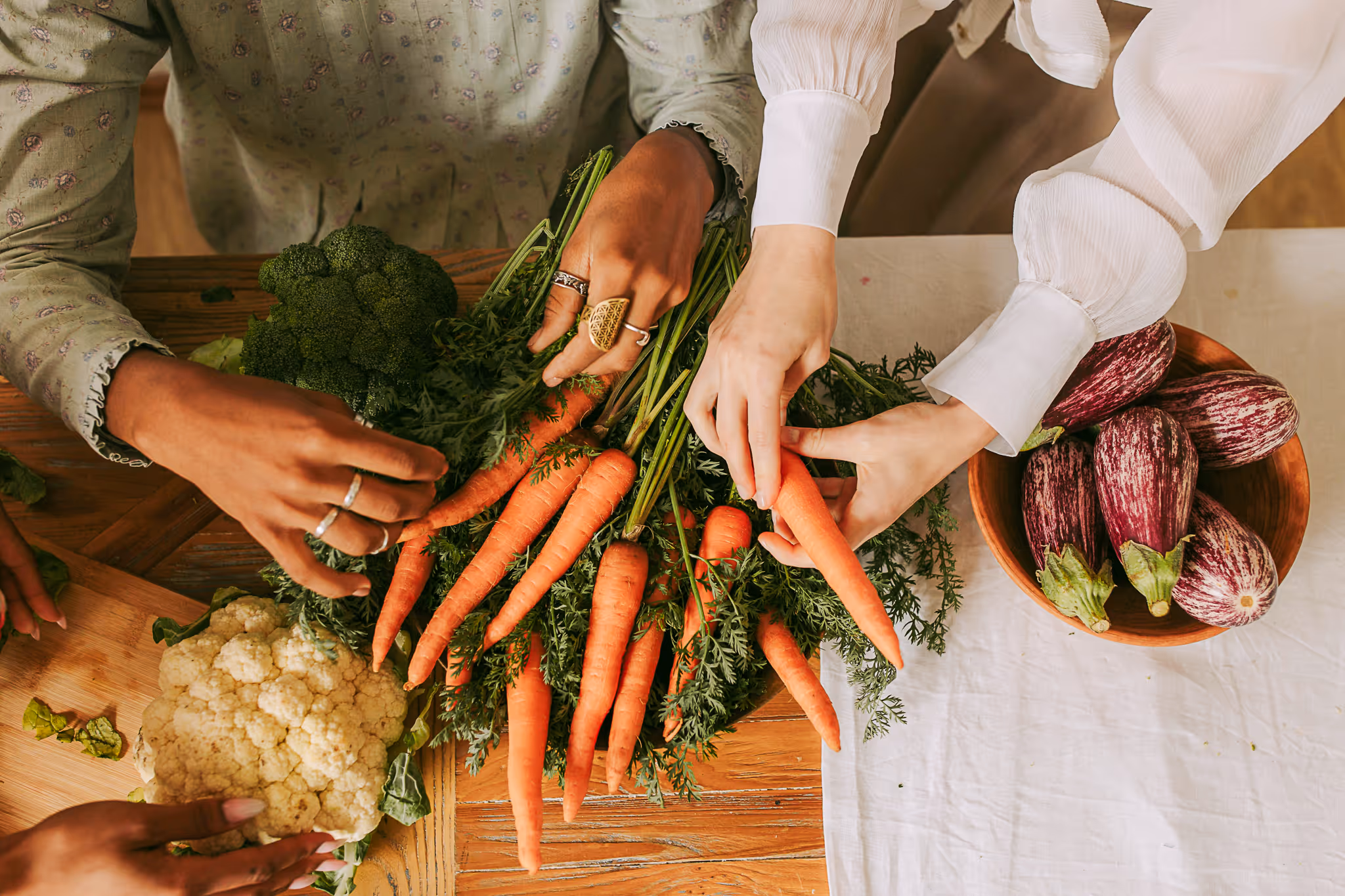 Hands sorting fresh carrots and vegetables on a kitchen cutting board