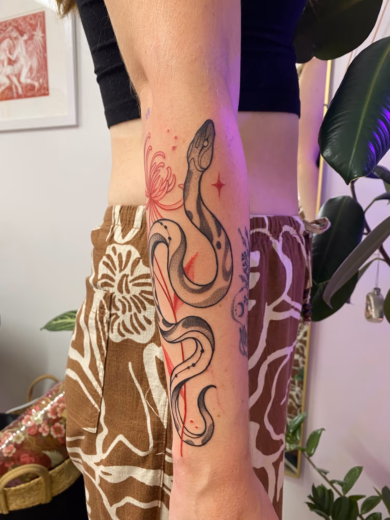 Black and grey forearm snake tattoo with red flower and star accents, by Alyssa at Vale of the Fae in Castlegar, BC