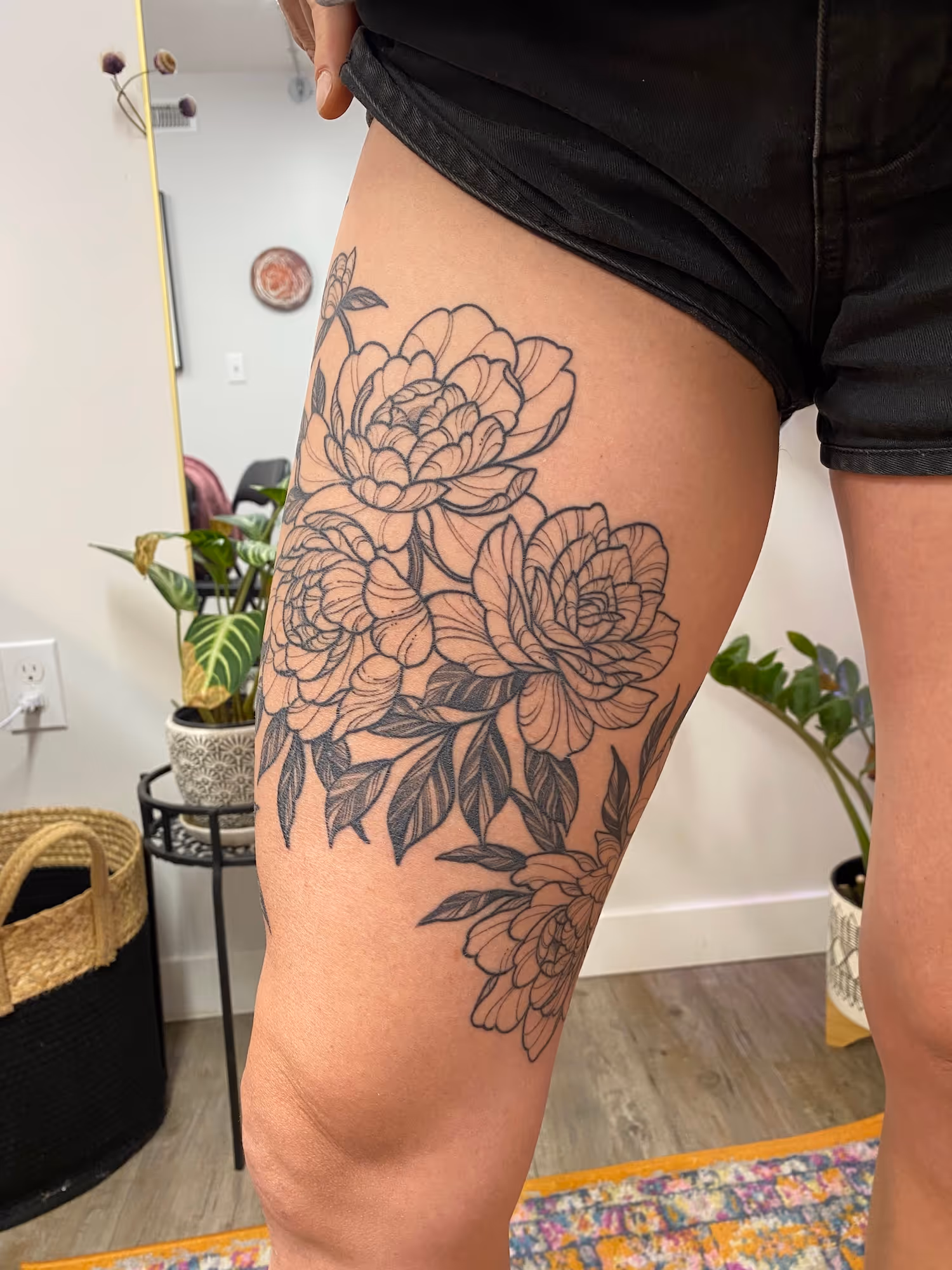 Blackwork floral thigh tattoo with detailed petals and leaves, by Alyssa at Vale of the Fae in Castlegar, BC