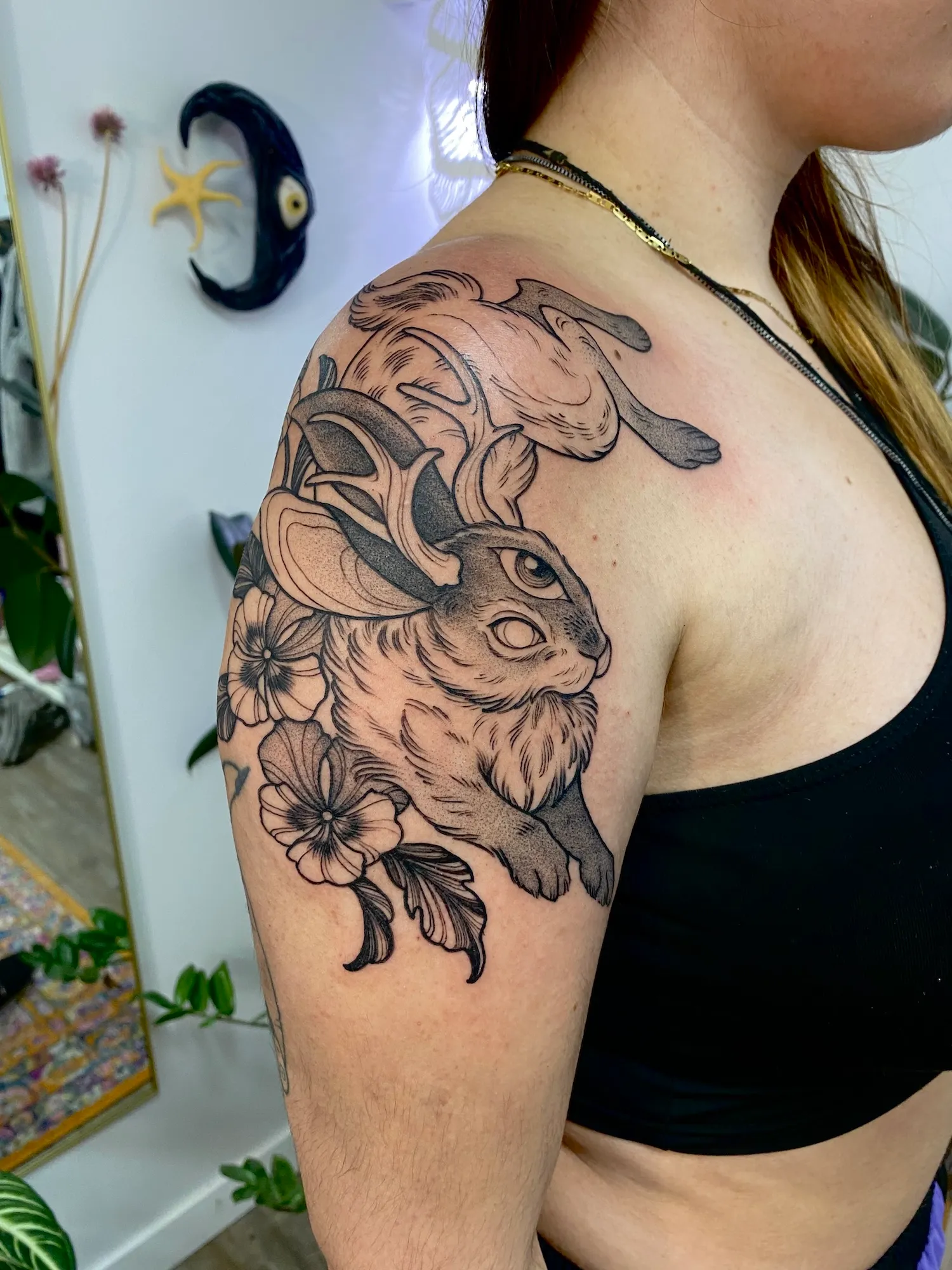 Black and grey jackalope tattoo with antlers and flowers on the upper arm and shoulder, by Alyssa at Vale of the Fae in Castlegar, BC
