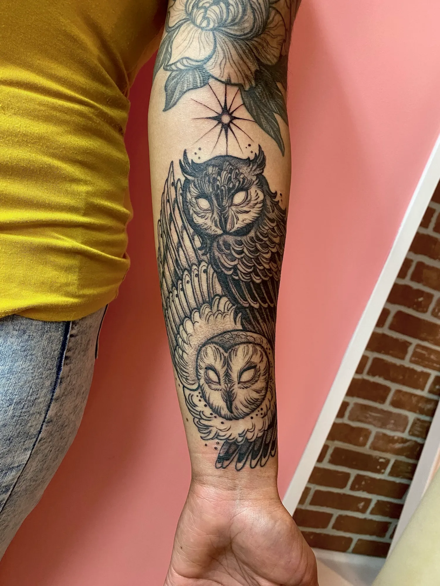 Blackwork forearm tattoo of two stylized owls beneath a star, by Alyssa at Vale of the Fae in Castlegar, BC